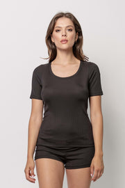 Kobieta stoi na prostym, jasnym tle, ubrana w dopasowaną bluzkę Loungewear z krótkim rękawkiem w prążek - czarną i pasujące czarne szorty. Twarz zwrócona do przodu, ręce rozluźnione po bokach, neutralny wyraz twarzy.