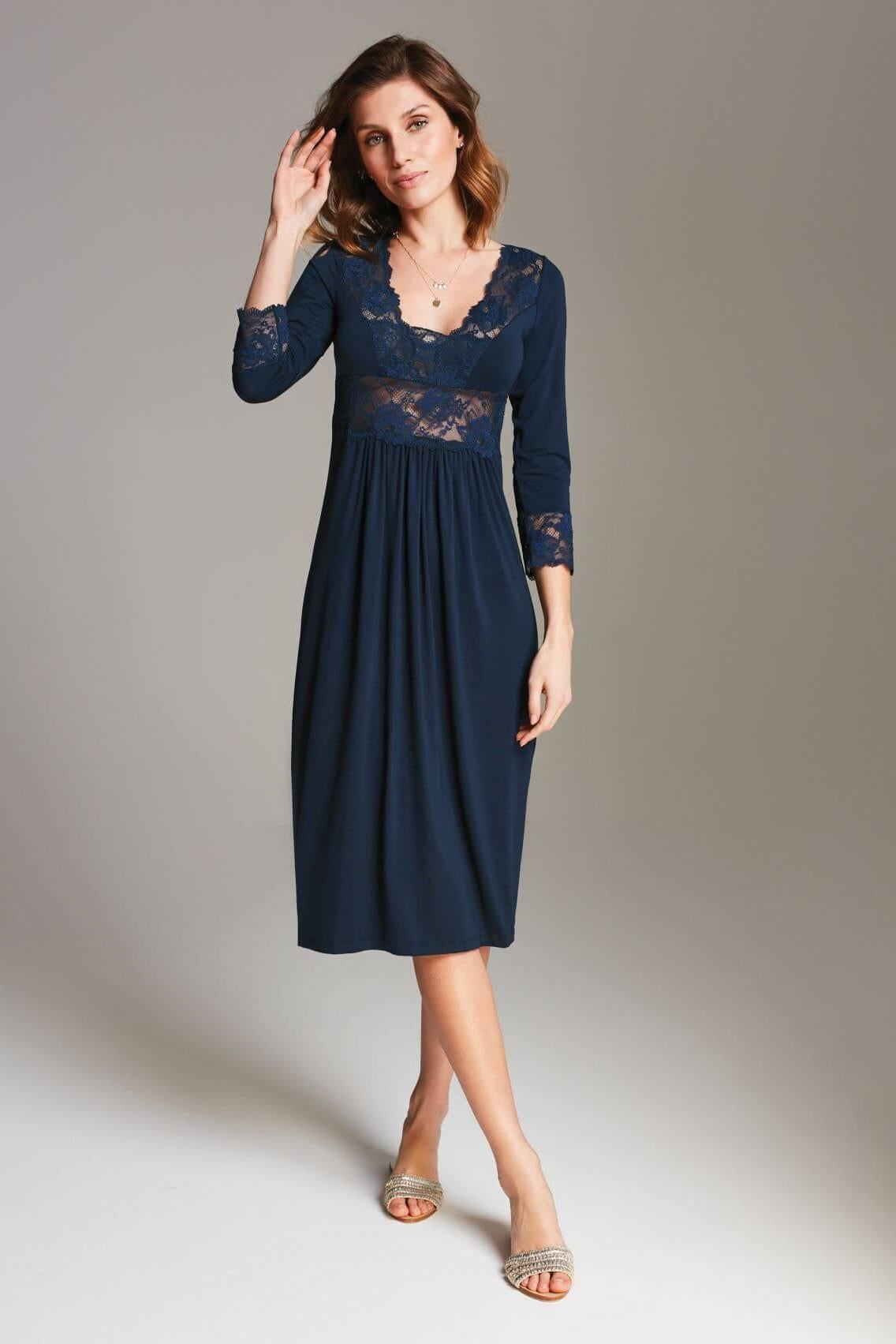 Kobieta pozuje w studio w koszuli nocnej Stars midi z koronką - granatowej koszuli nocnej do kolan z delikatną koronką na piersi i rękawach, wykonanej z miękkiej dzianiny wiskozowej, na neutralnym tle.